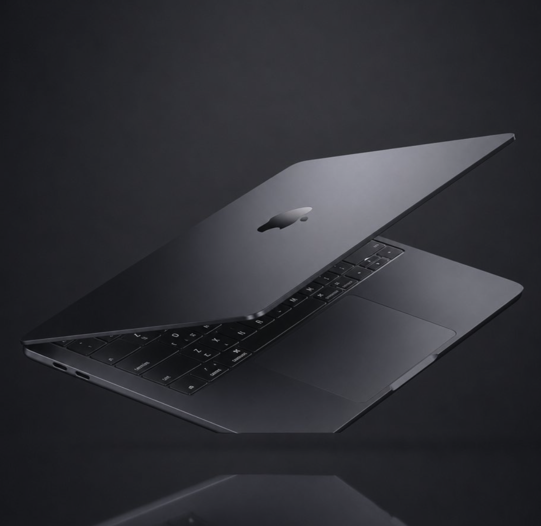 A dark-colored Apple MacBook laptop shown partially open against a dark reflective surface.