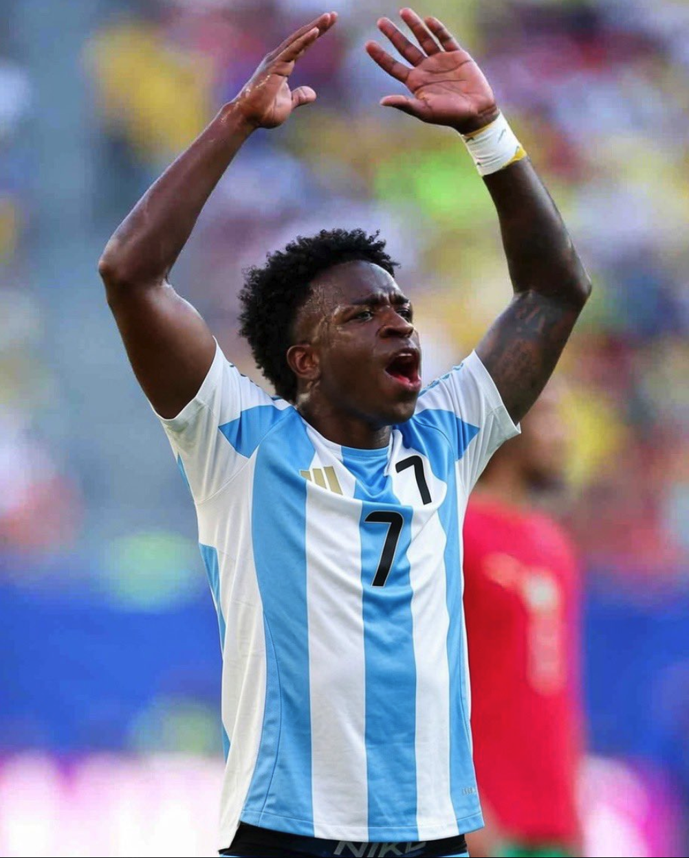 Vinícius Júnior in an Argentina national team #7 jersey with both arms raised in celebration.