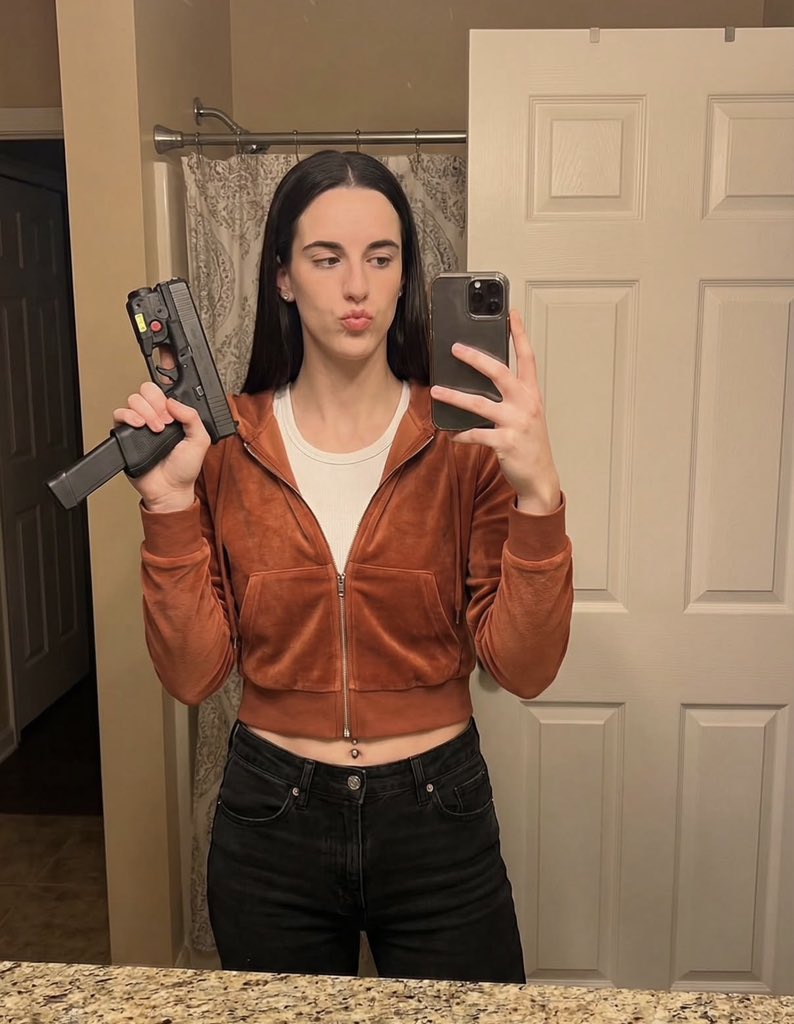 A woman resembling Caitlyn Clark taking a mirror selfie while holding a handgun indoors.