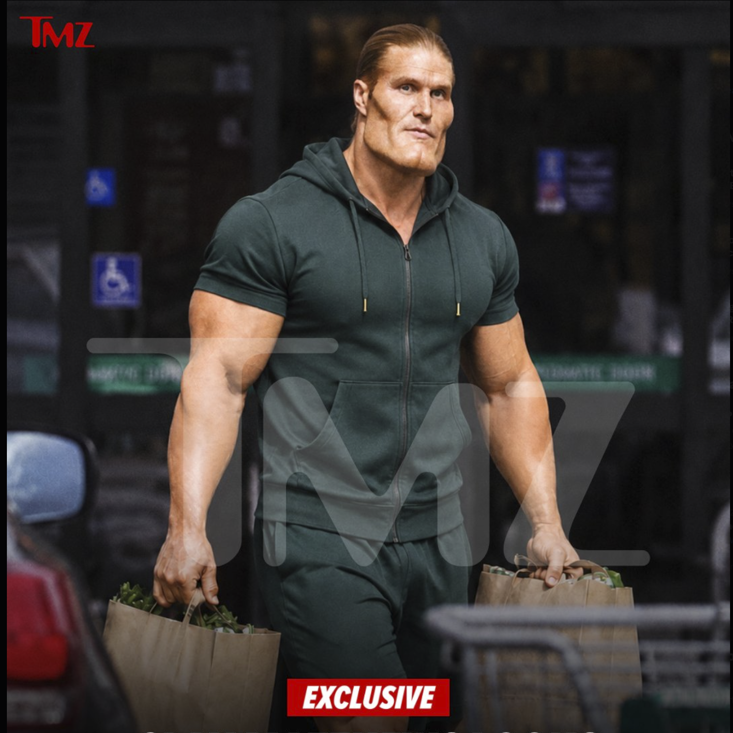 A man resembling Clay Matthews III carrying paper grocery bags outside a store.