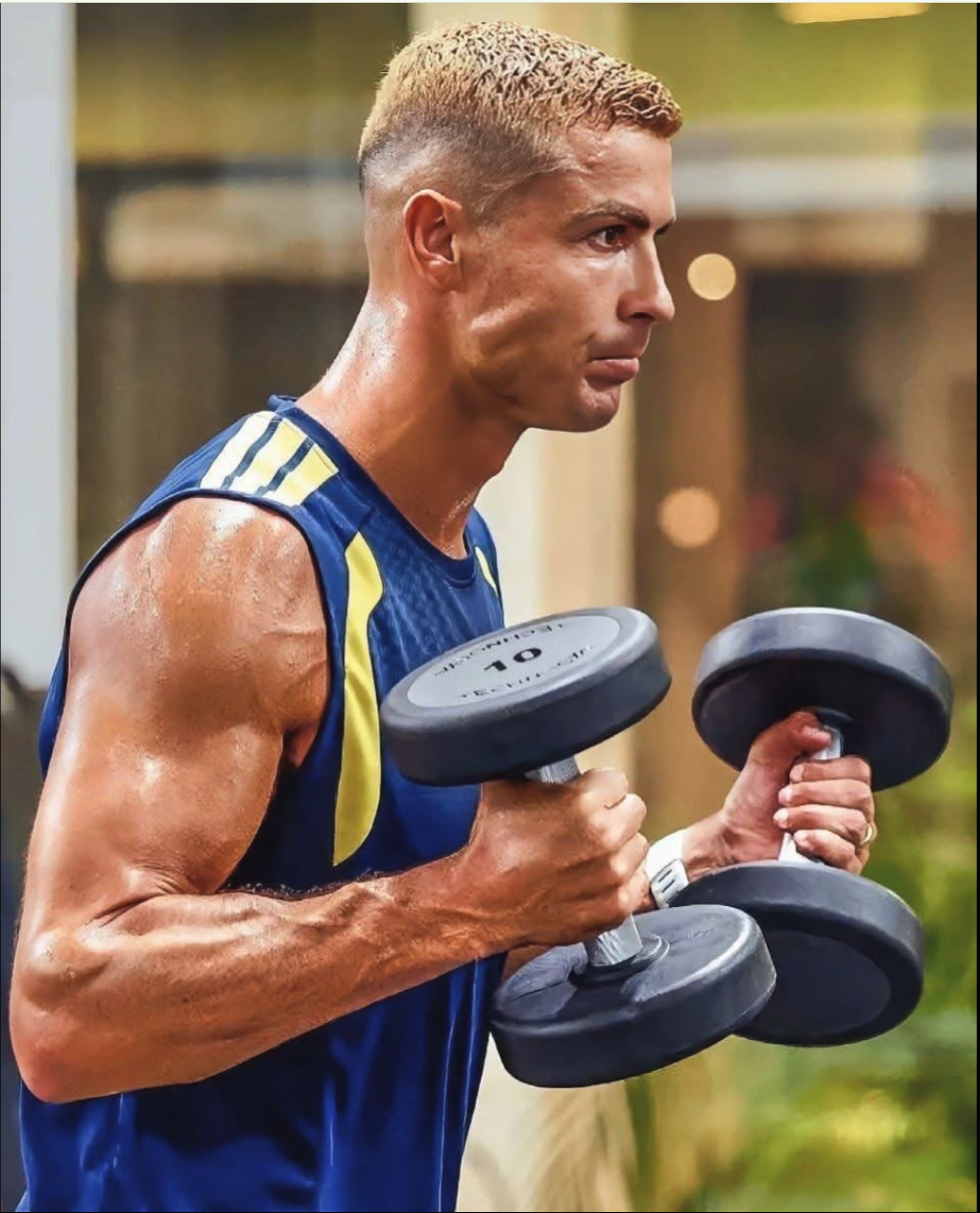 A muscular man resembling Cristiano Ronaldo in profile, lifting two dumbbells while wearing a blue and yellow sleeveless athletic top.
