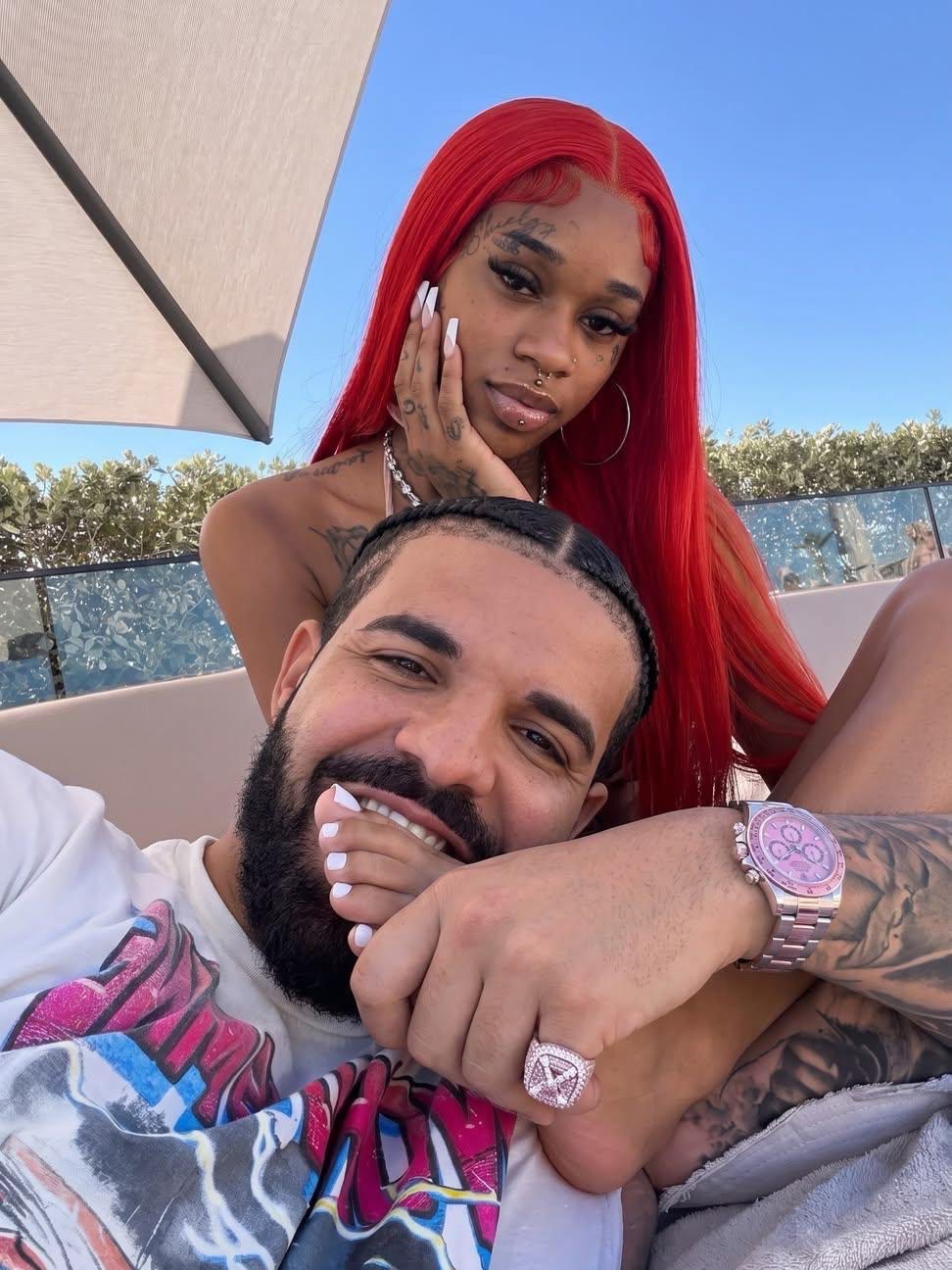 A man resembling Drake taking a selfie with a woman resembling Sexyy Red on an outdoor sun lounger.