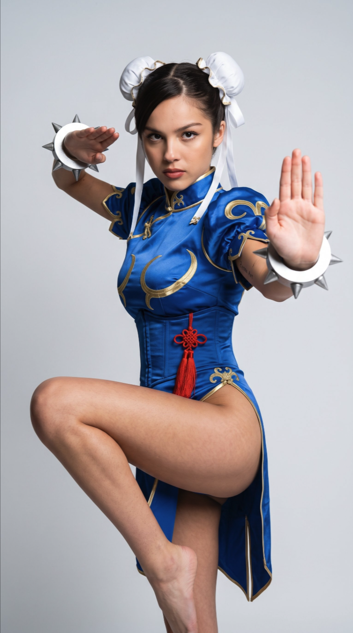 A woman resembling Fei Fei Sun posed in a fighting stance as Street Fighter character Chun-Li, wearing a blue qipao with spiked bracelets.
