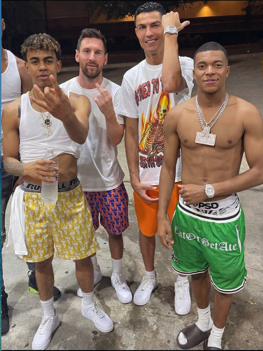 Four men standing together outdoors at night in casual and athletic clothing.