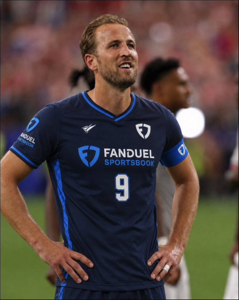 A man resembling Harry Kane standing on a pitch wearing a navy FanDuel Sportsbook #9 jersey.