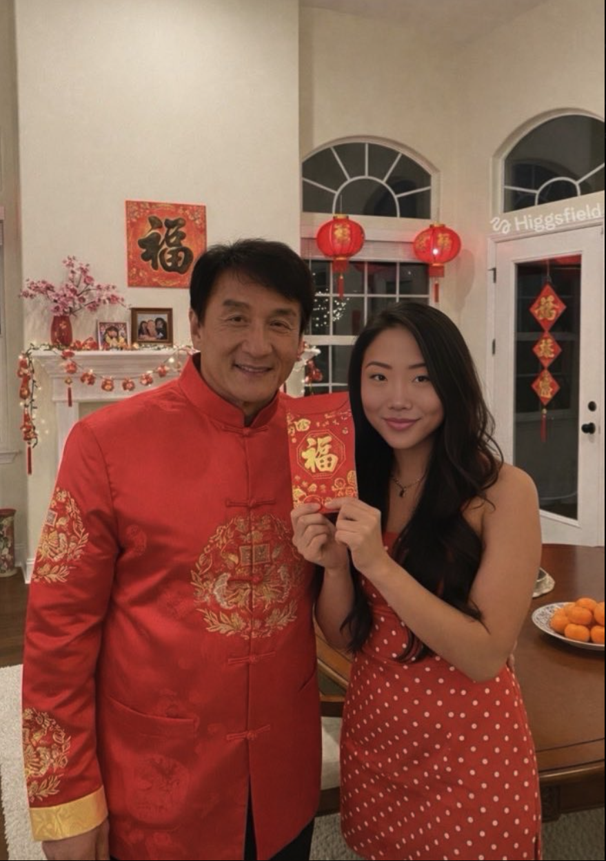 An older man resembling Jackie Chan and a young woman in red holding a red Chinese New Year envelope together indoors.