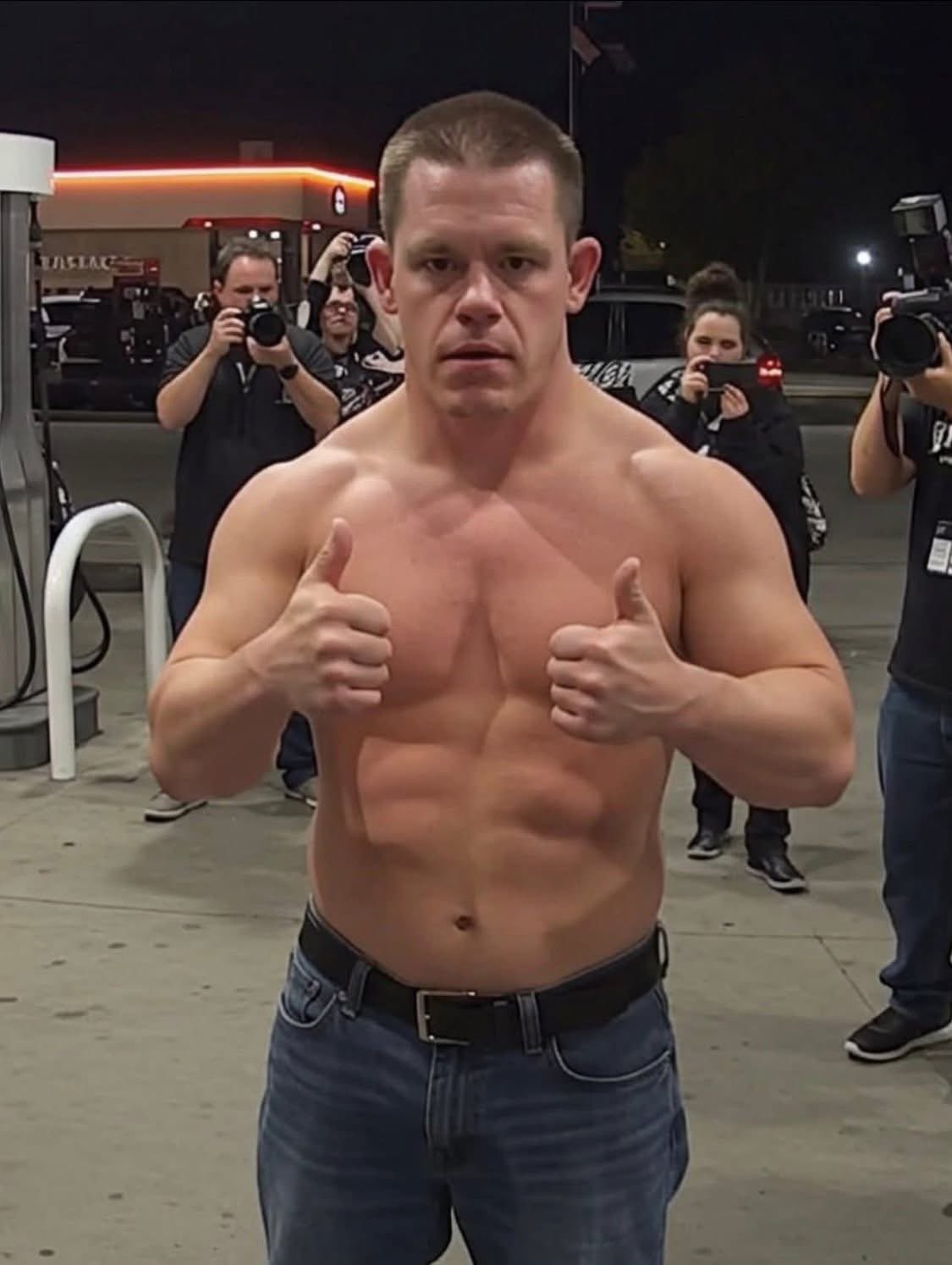 A shirtless, muscular man resembling John Cena giving two thumbs up at a gas station at night.