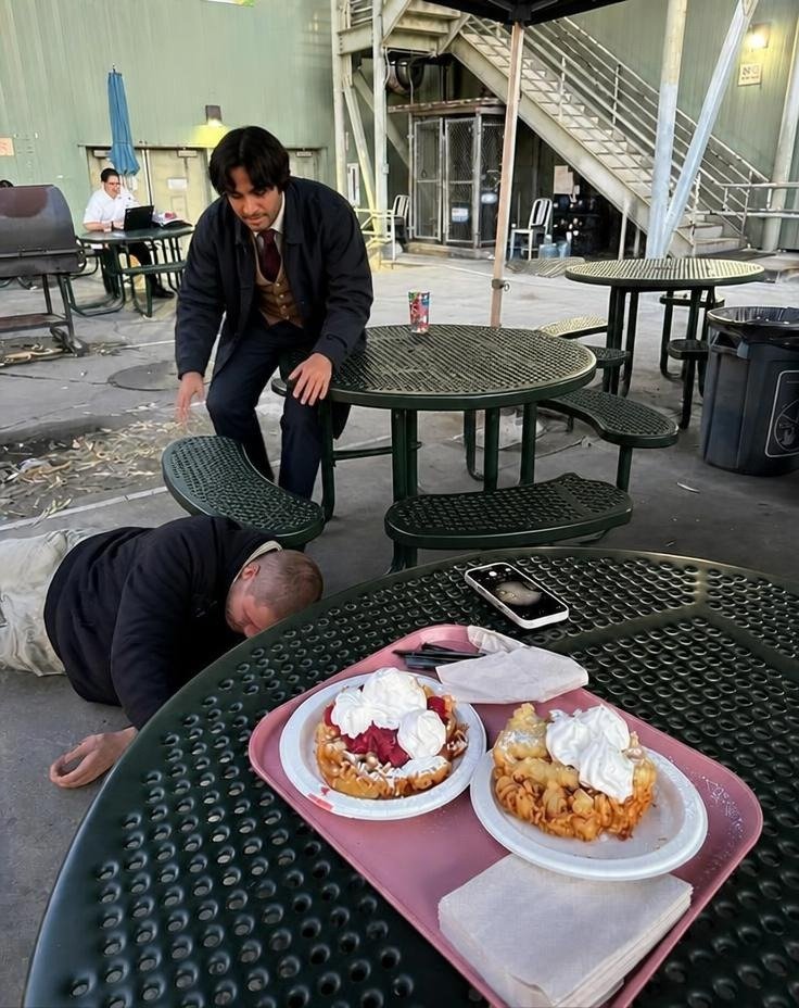 An AI image appearing to show Justin Bieber beside patio tables, with one crouching and two desserts nearby.