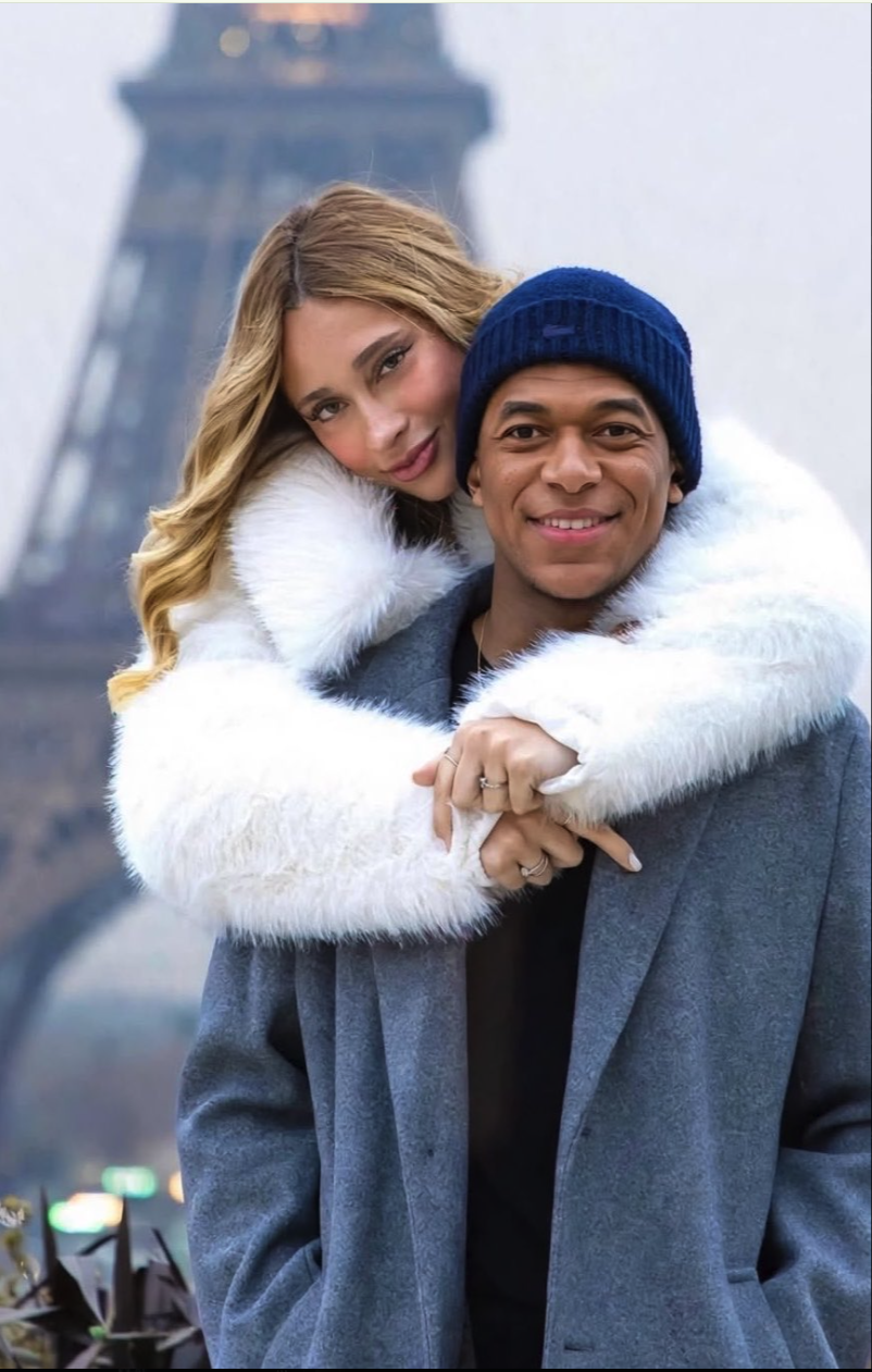A man resembling Kylian Mbappé embracing an unidentified woman in front of the Eiffel Tower.