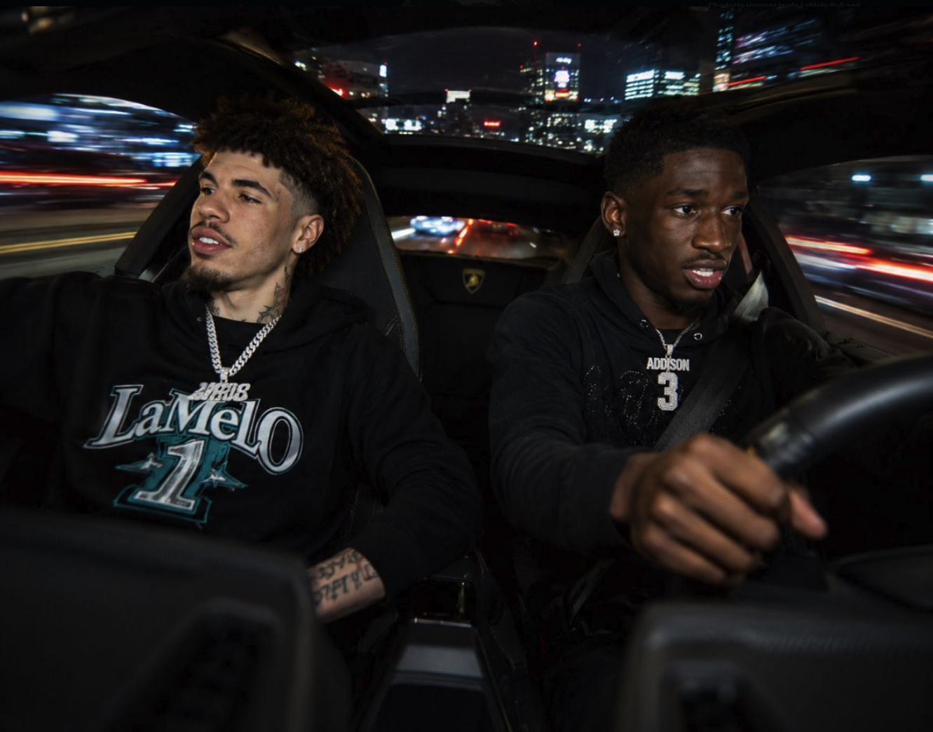 Two men resembling LaMelo Ball and Jordan Addison seated inside a Lamborghini at night.