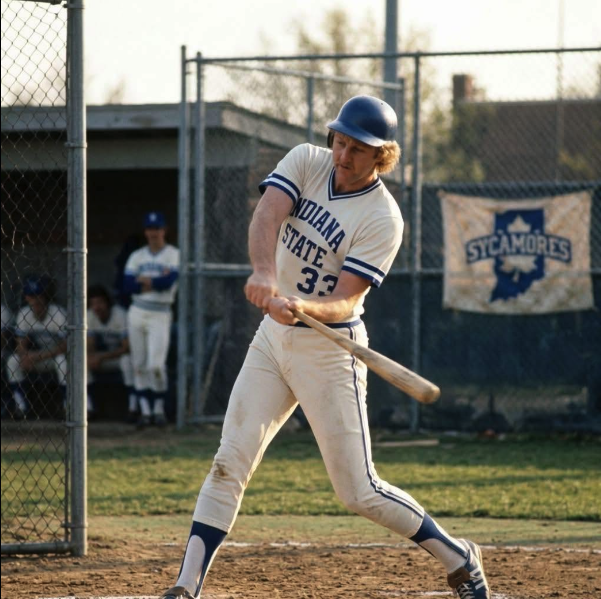 A baseball player resembling Larry Bird mid-swing in a cream Indiana State #33 uniform.