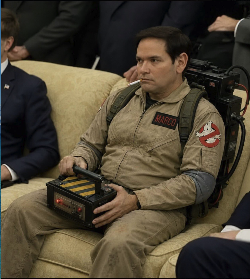 A man resembling Marco Rubio seated in a tan Ghostbusters-style jumpsuit with a 'MARCO' name patch and proton pack equipment.
