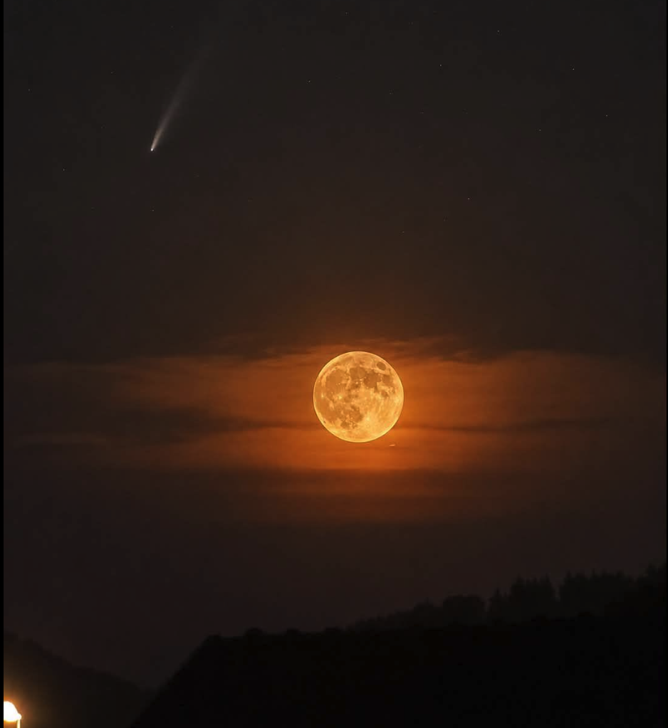 A glowing orange full moon in a dark night sky with a bright comet streak in the upper left.