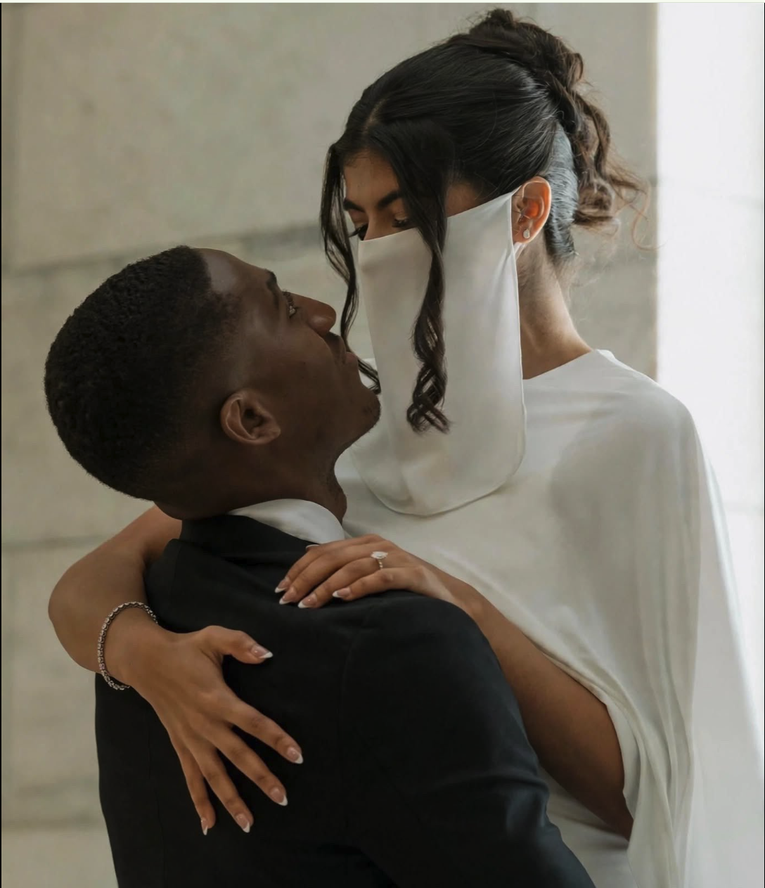A man resembling Ousmane Dembélé embracing a woman in a white wedding dress and veil.