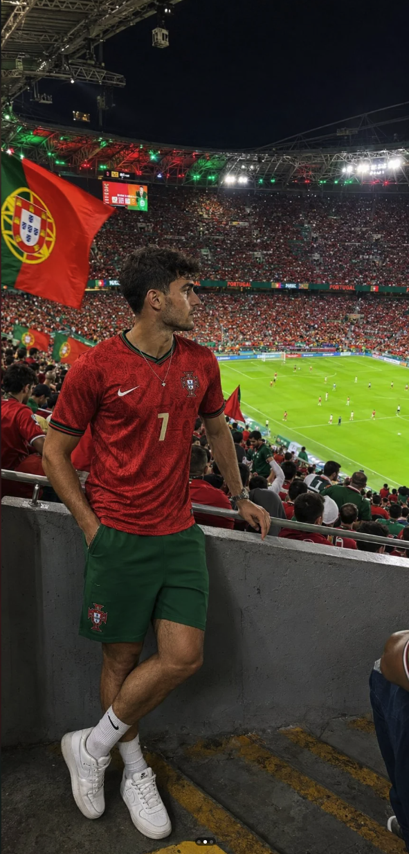 A person resembling a young man in a Portugal national football jersey standing at a stadium during a match.