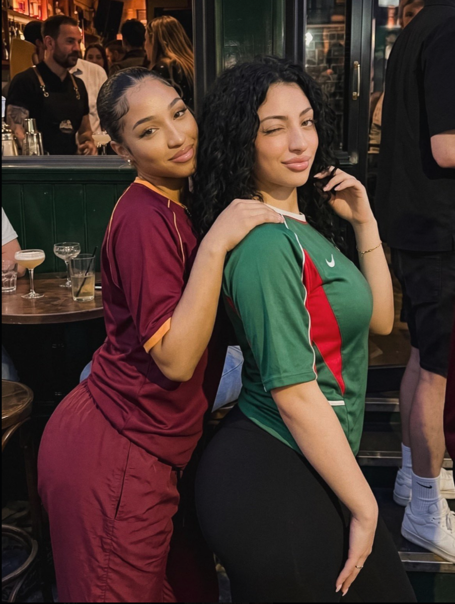 Two women posing together at a bar.