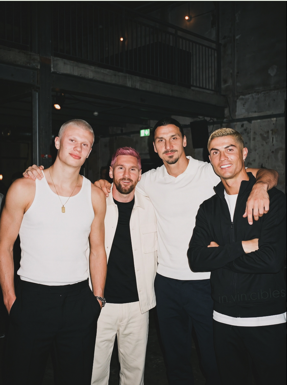 Four men resembling Cristiano Ronaldo, Lionel Messi, and two others posing together indoors.