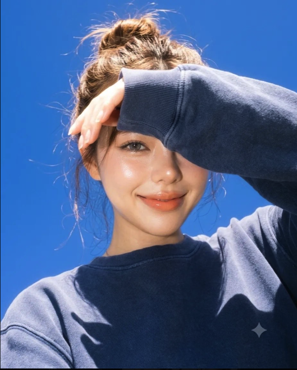 An unidentified woman smiling and shielding her eyes against a clear blue sky.