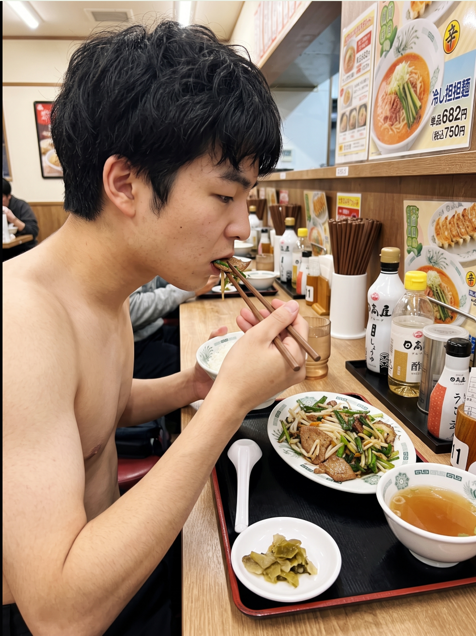 A shirtless young man eating noodles with chopsticks at a Japanese restaurant counter.