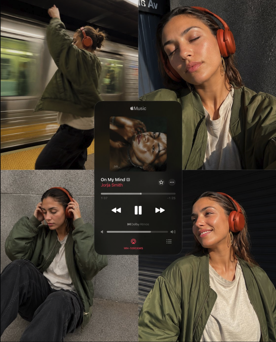 A woman wearing red over-ear headphones and a green bomber jacket in a subway station.