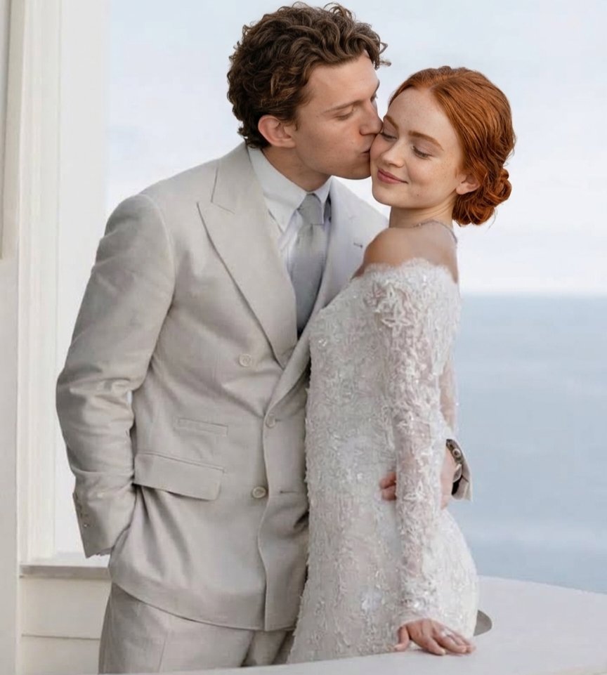 A man resembling Tom Holland kissing the forehead of a red-haired woman resembling Sadie Sink, both in wedding attire by the sea.