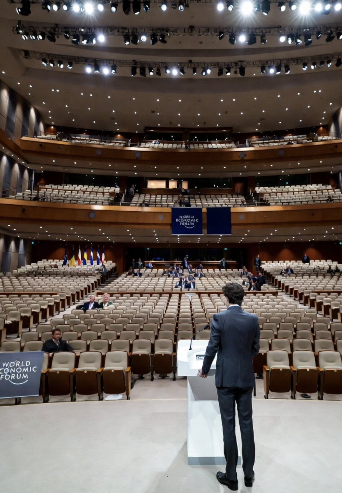 A man resembling Justin Trudeau at a podium addressing a nearly empty World Economic Forum auditorium.