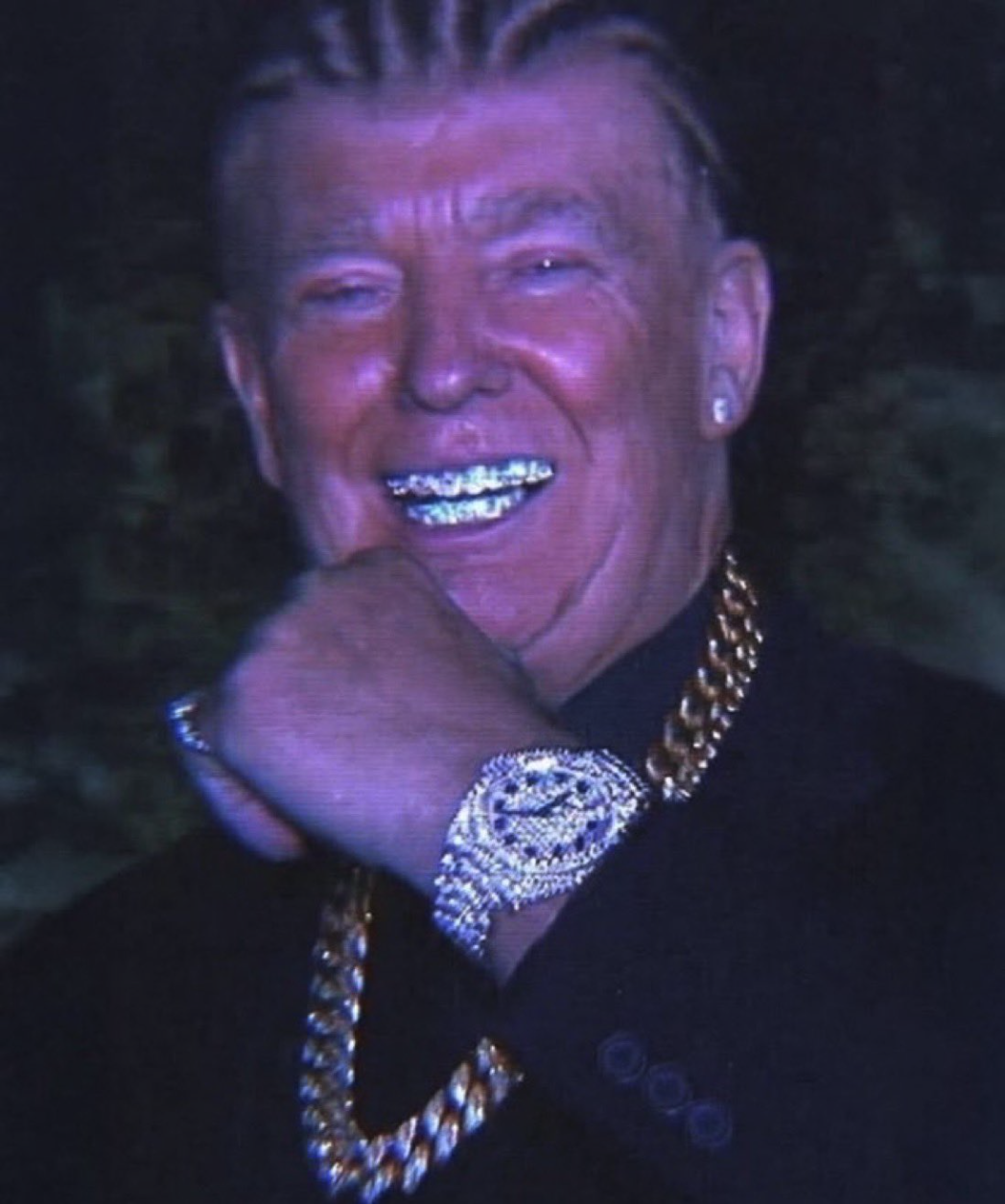 A man resembling Donald Trump smiling to show diamond-encrusted grills, wearing heavy gold chains over a dark top.
