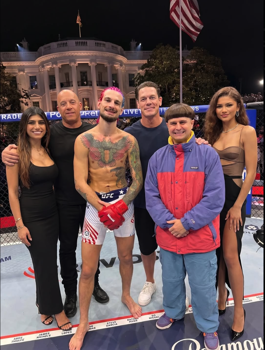 Six people resembling Sean O'Malley, John Cena, Vin Diesel, Zendaya, Mia Khalifa, and Oliver Tree pose together inside a UFC octagon at night, with the White House behind them.