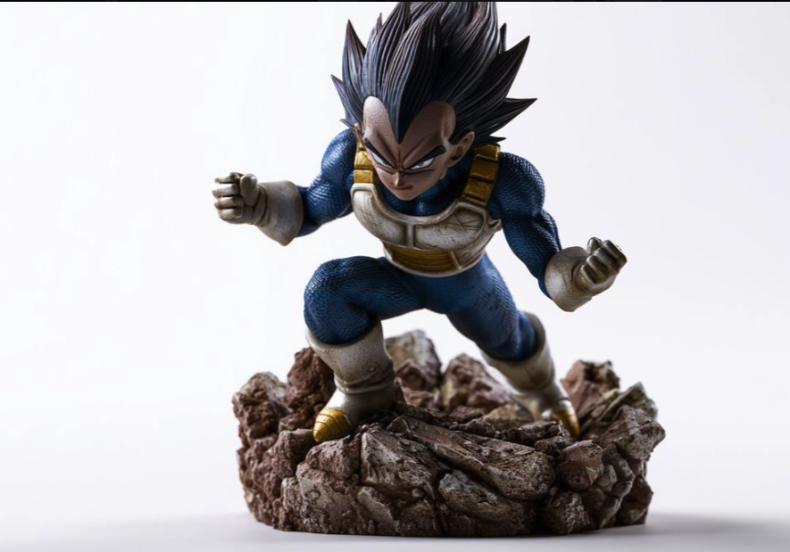 A painted figurine depicting Vegeta from Dragon Ball Z in a crouched battle pose on a rocky debris base.