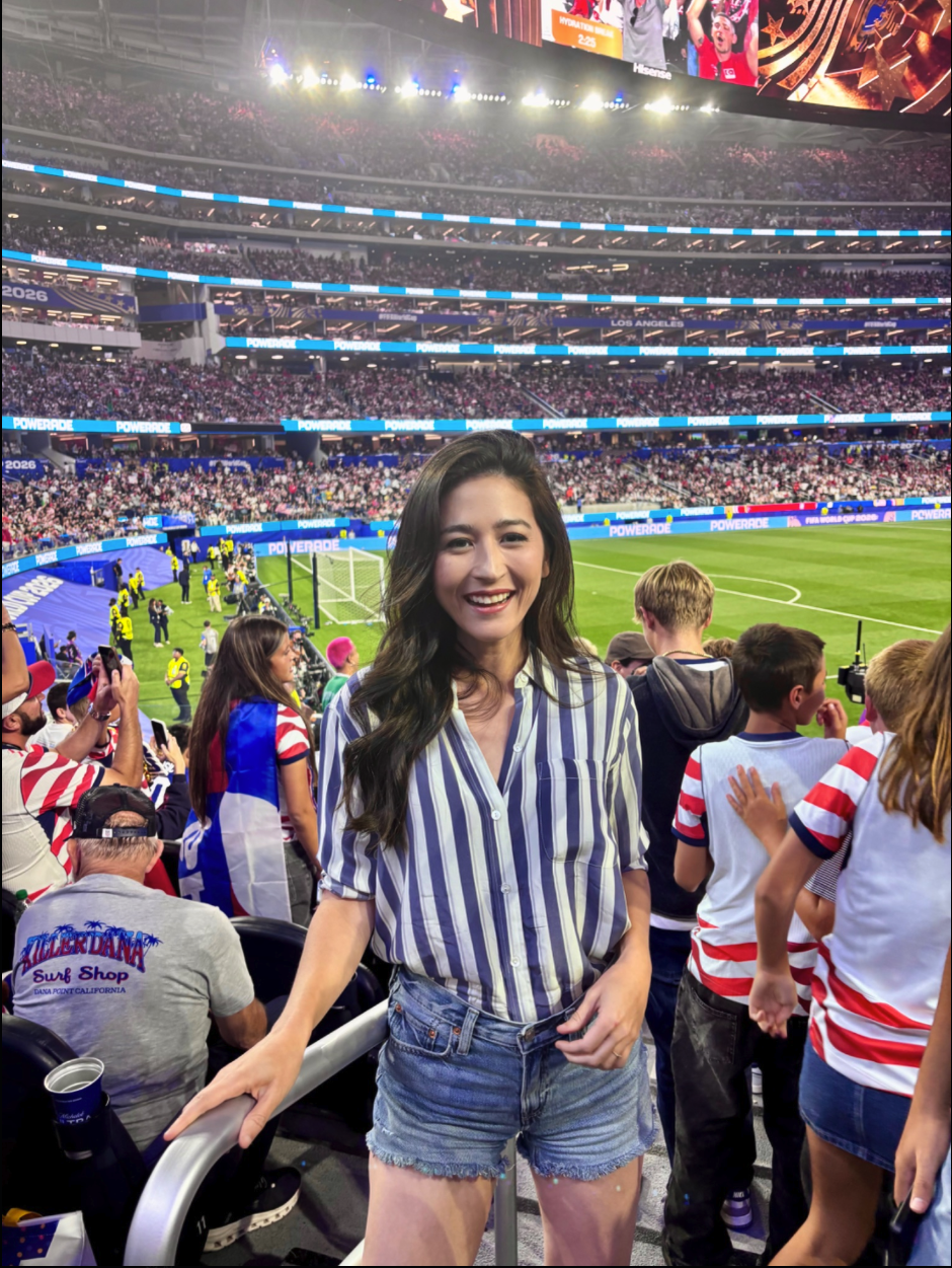 A woman smiling at a FIFA World Cup 2026 match in a Los Angeles stadium.