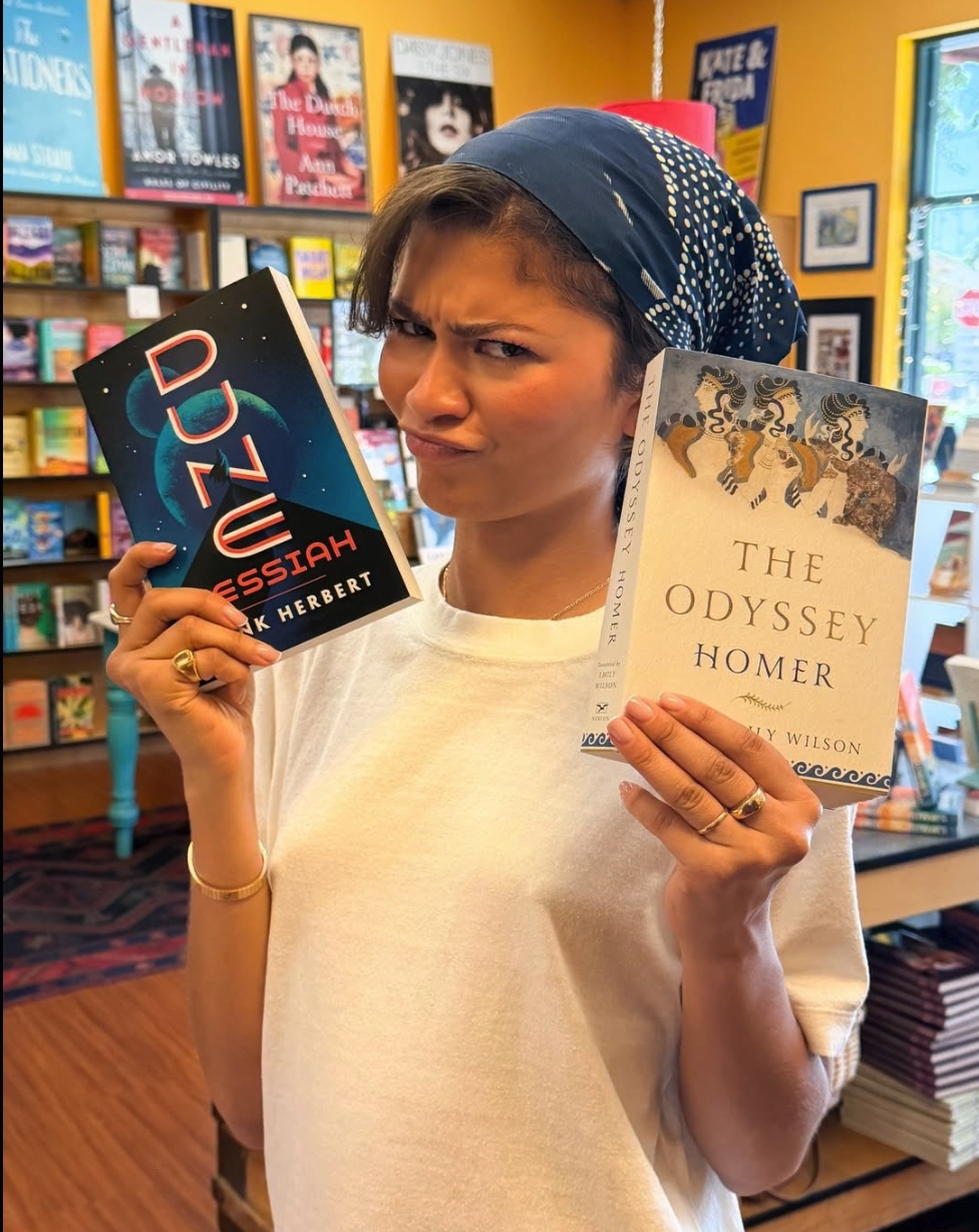 A woman resembling Zendaya holding copies of Dune Messiah and The Odyssey in a bookstore.