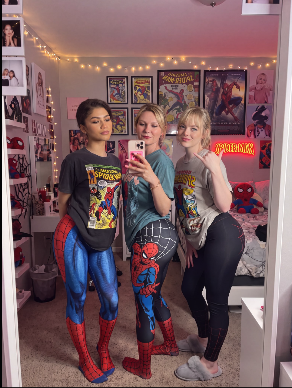 Three women resembling Zendaya, Kirsten Dunst, and Emma Stone posing for a mirror selfie in Spider-Man leggings and graphic tees.