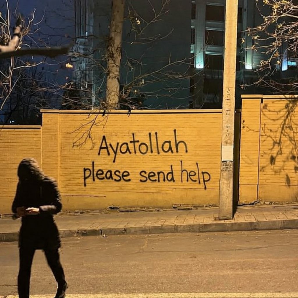 A man resembling Donald Trump in a dark hooded jacket looking at a phone, with 'Ayatollah please send help' graffiti on a yellow wall behind.