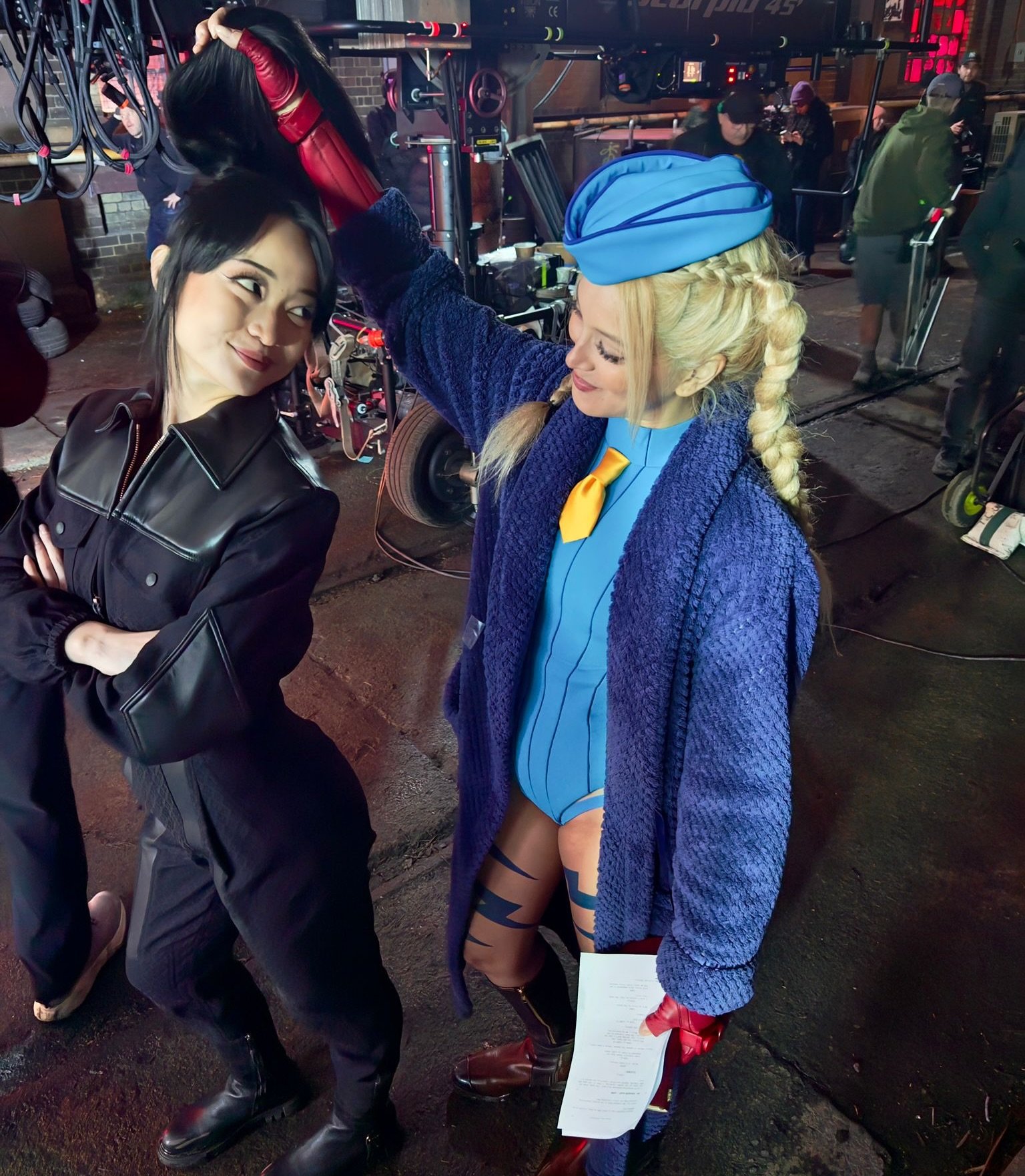 Two women in costume resembling Callina Liang and Mel Jarnson standing together on a film set at night.