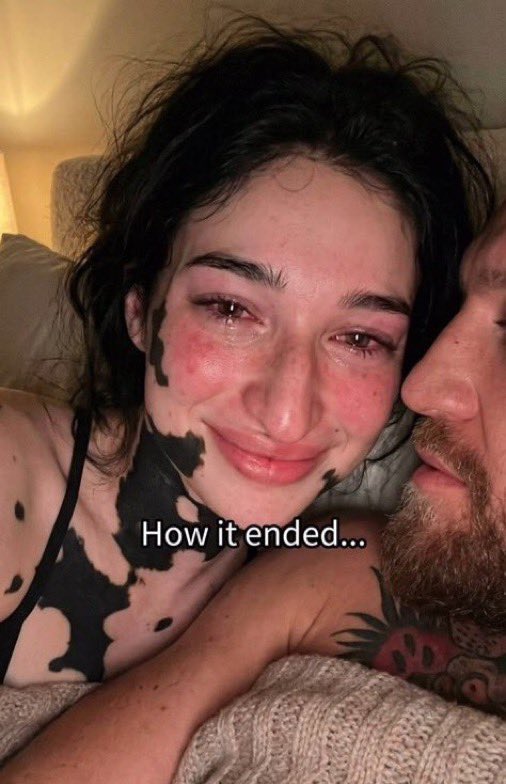 A man resembling Conor McGregor lying beside a dark-haired woman in a close-up selfie.