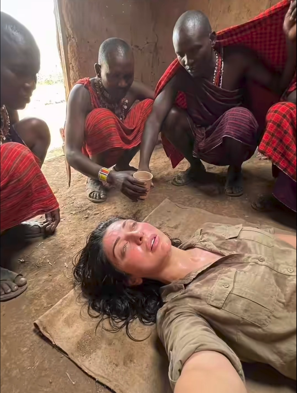 A woman resembling Garima Ajmani lying on a mat surrounded by figures in traditional red cloth clothing.