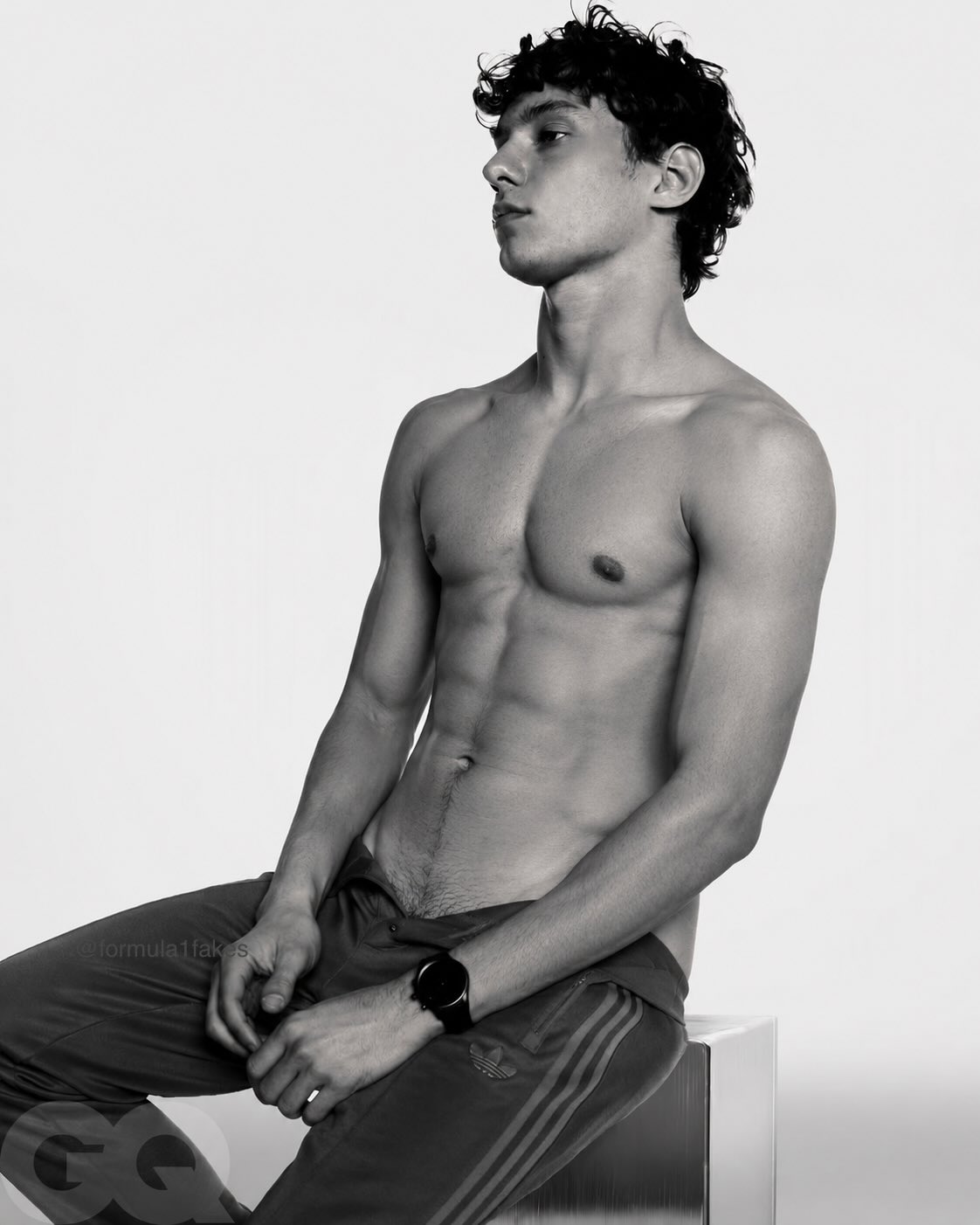 A young man resembling Kimi Antonelli, shirtless and seated in a black-and-white GQ-style editorial photo.