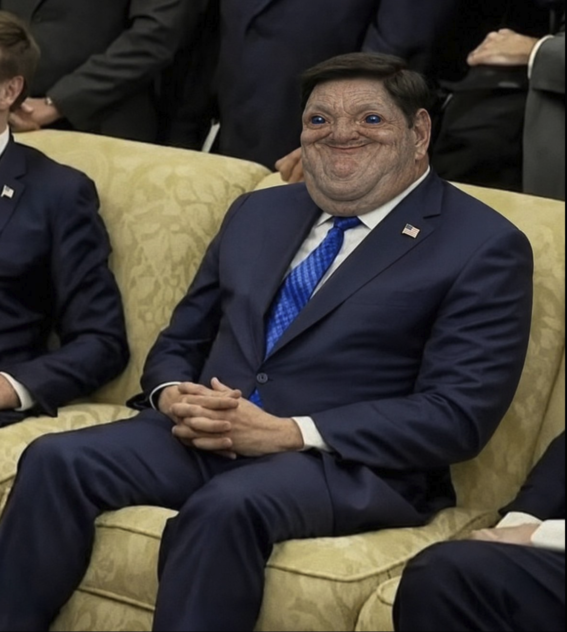 A man resembling Marco Rubio seated on a yellow couch in a dark suit and blue tie.