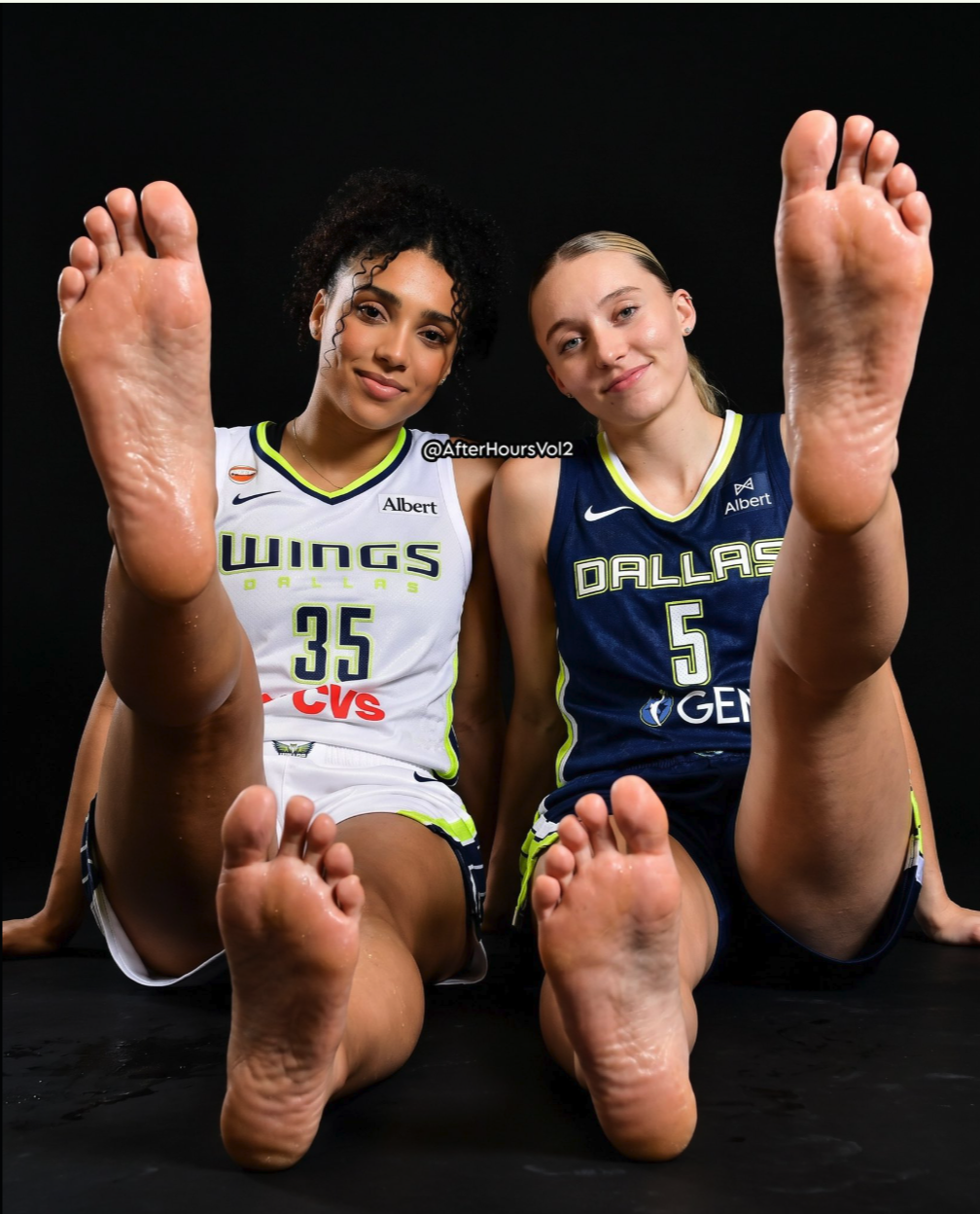 Two women resembling Paige Bueckers and Azzi Fudd seated in Dallas basketball jerseys with bare feet extended toward the camera.