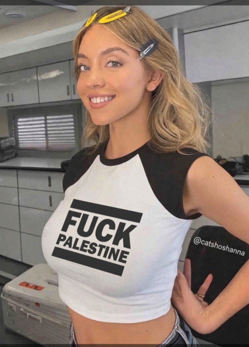 A woman resembling Sydney Sweeney smiling in a selfie, wearing a black-and-white crop top.