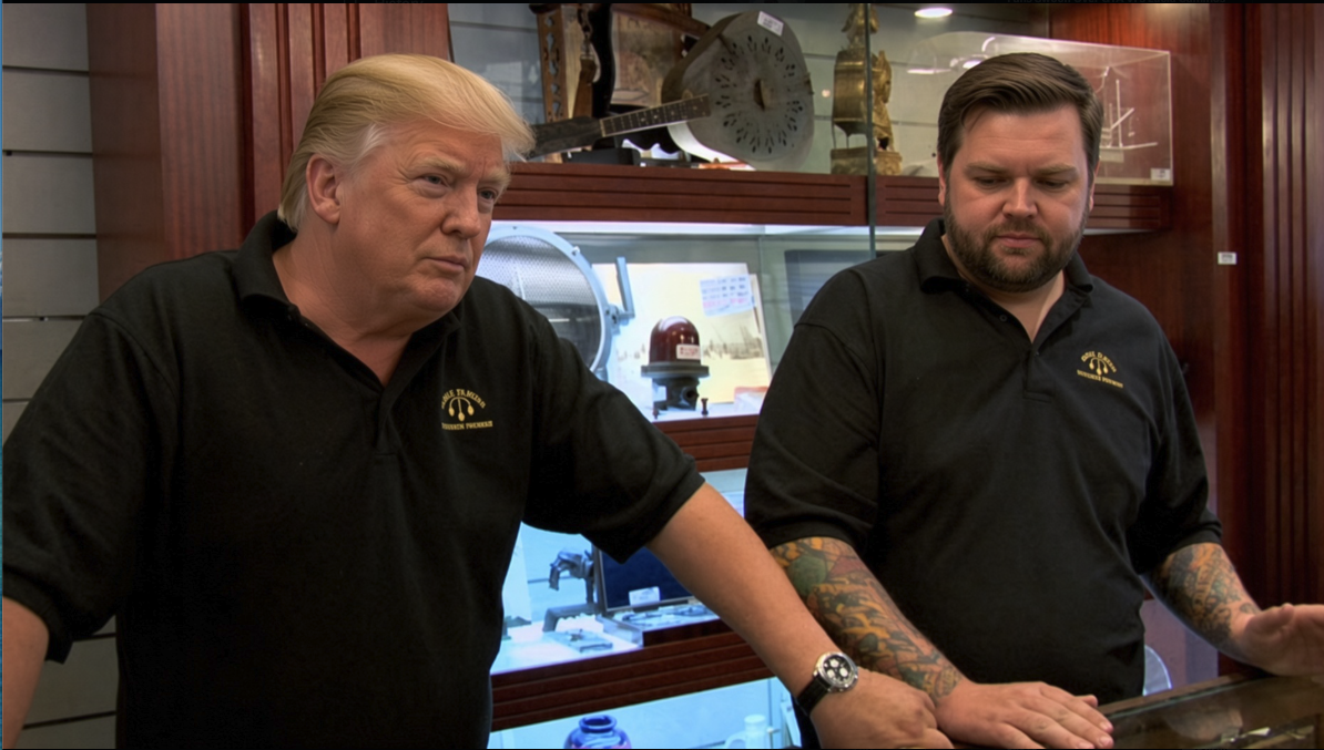 Two men resembling Donald Trump and JD Vance standing behind a counter in a museum gift shop wearing matching black polo shirts.