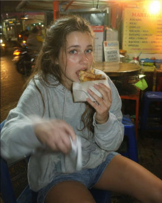 AI-generated image of a woman eating martabak at an Indonesian street food stall