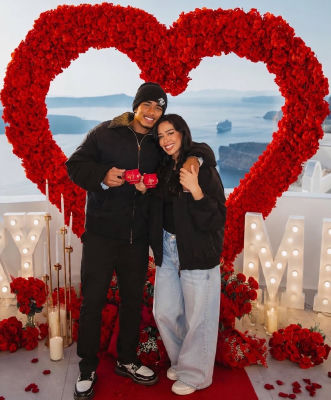 AI-generated image of Jude Bellingham and Ashlyn Castro posing by a red rose heart in Santorini