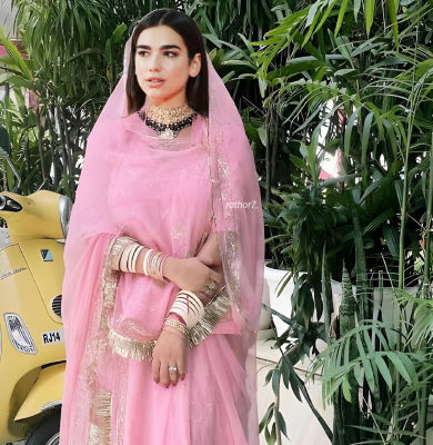 Deepfake of Dua Lipa in pink traditional Indian outfit beside a yellow Vespa