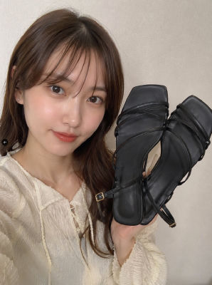 AI-generated image of a woman holding black heeled sandals