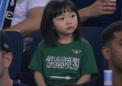 AI-generated image of a young child in a Saudi Arabian emblem shirt at a sporting event