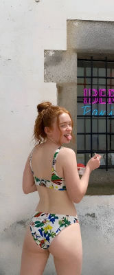 Deepfake image of Sadie Sink in a floral bikini posing on a street near a barbershop