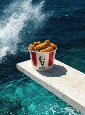 AI-generated image of a KFC bucket with Colonel Sanders logo on a diving board over the ocean