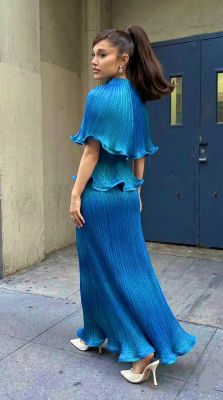 Deepfake of Ariana Grande in a blue pleated gown on a city sidewalk