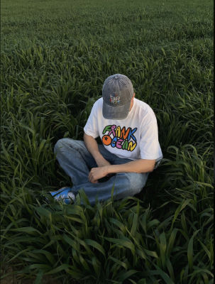 AI-generated image of a person in a Frank Ocean t-shirt sitting in a grass field